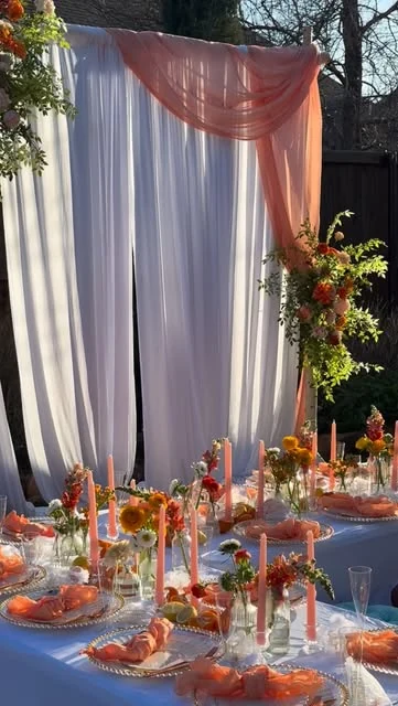 Warm floral table styling and draped backdrop by Junis