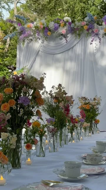 Garden reception adorned with colorful florals and soft white draping